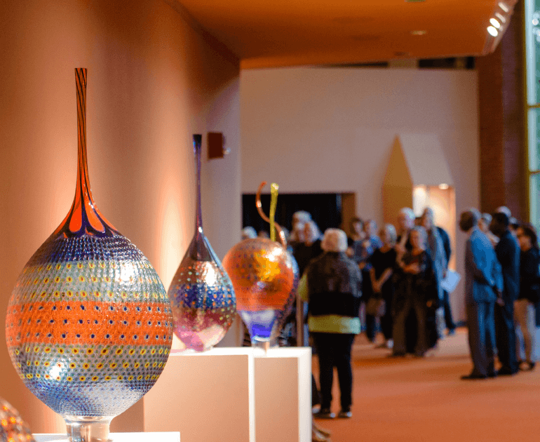 Glass artworks displayed with people in the background