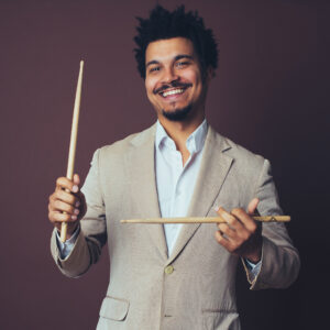 Charles Goold holding drum sticks and smiling