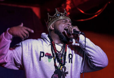 Man Wearing A Crown Holding Up A Microphone