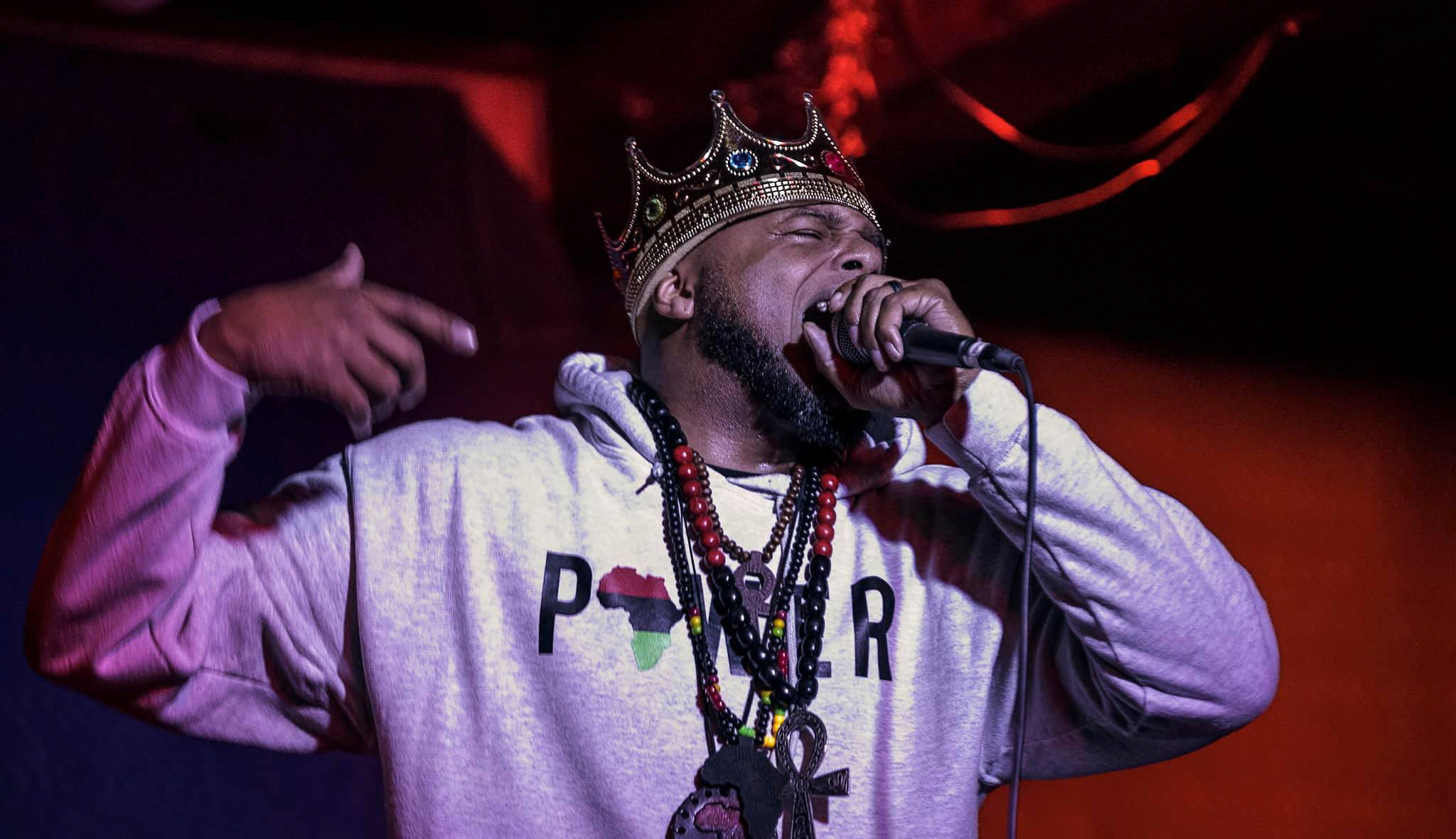 Man wearing a crown holding up a microphone