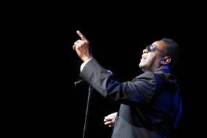 Al Green with a microphone in front of him, pointing upward.