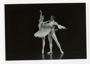 A male and female ballet dancer on stage mid movement. 