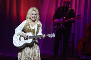 Dolly Parton singing on stage holding a guitar