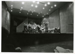 L'Orchestre de Paris performing on stage. A conductor stands at the front with his hands up.