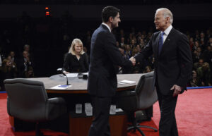 Paul Ryan and Joe Biden shake hands in front of the onlooking audience.