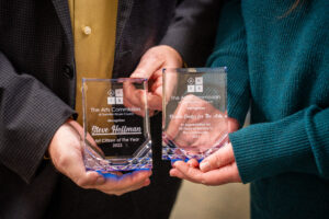Two sets of hands holding the Arts Citizen of the Year award and the Arts Organization of the Year award