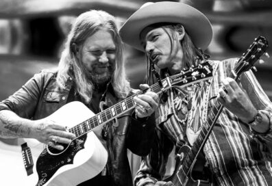 Black And White Photograph Of Allman Betts Playing Guitars Next To One Another