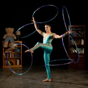 Cirque Us performer spinning 6 hula hoops on his hands, feet and legs.