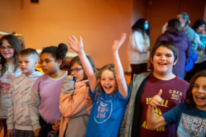 K-12 students smiling and cheering in the Norton Center lobby