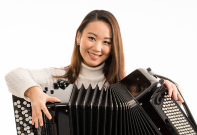 Hanzhi Wang Holding Her Accordion And Smiling At The Camera