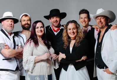 The Seven Wonders Band Members Pose And Smile Against A Gray Background