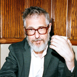 Ira Glass headshot, with him holding up a mug