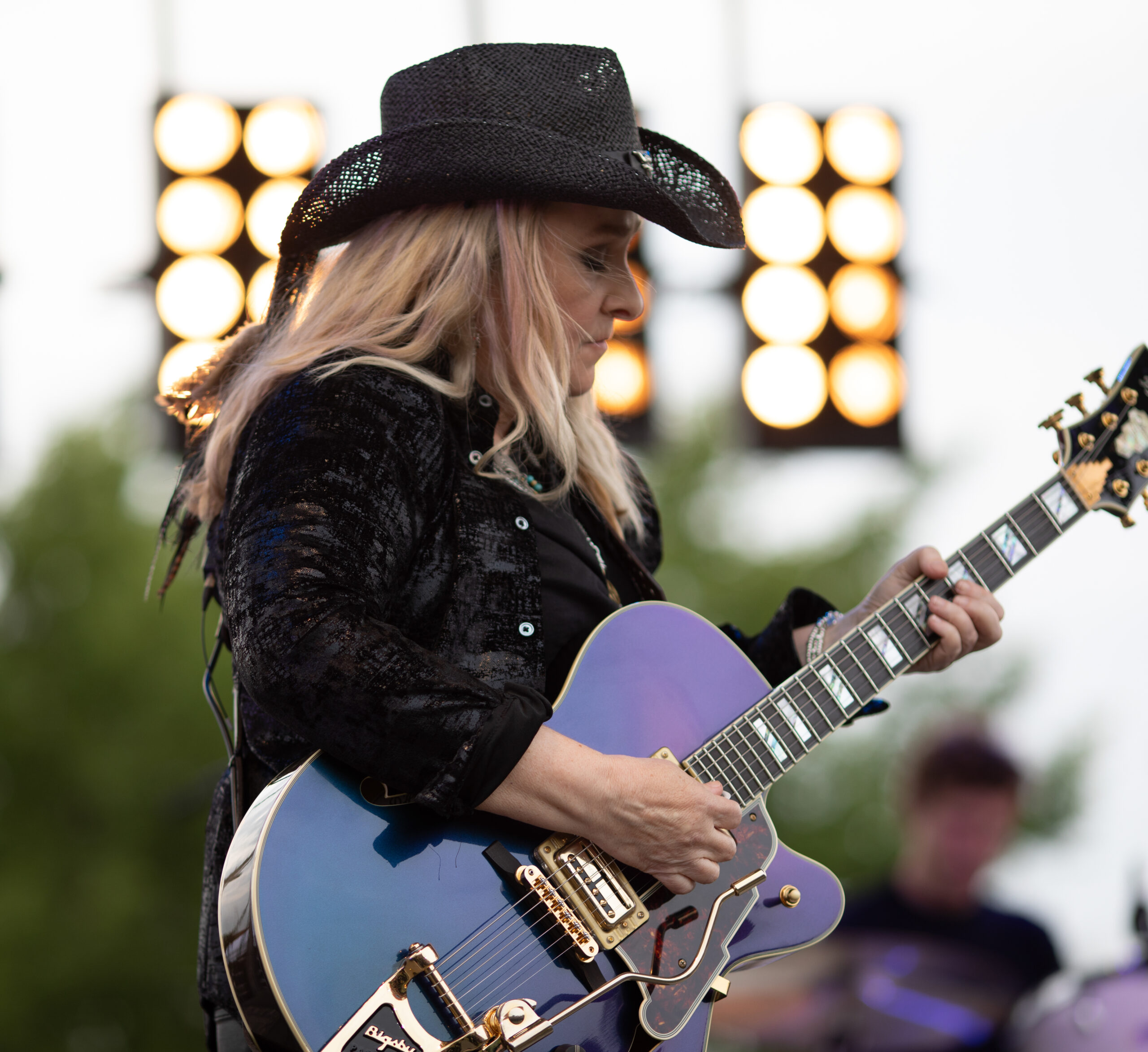 Melissa Etheridge playing her guitar in front of stage lights