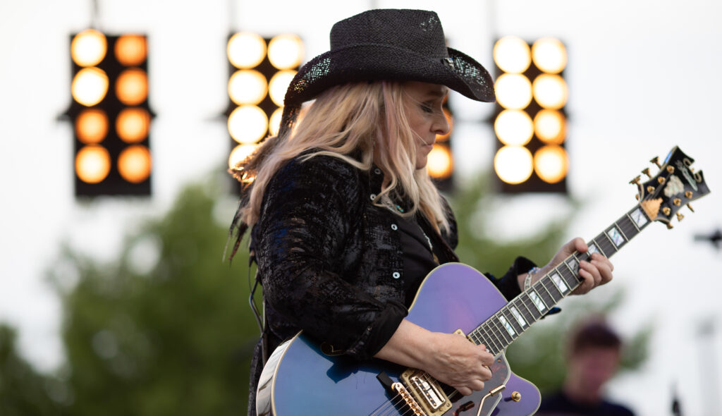 Melissa Etheridge playing her guitar in front of stage lights
