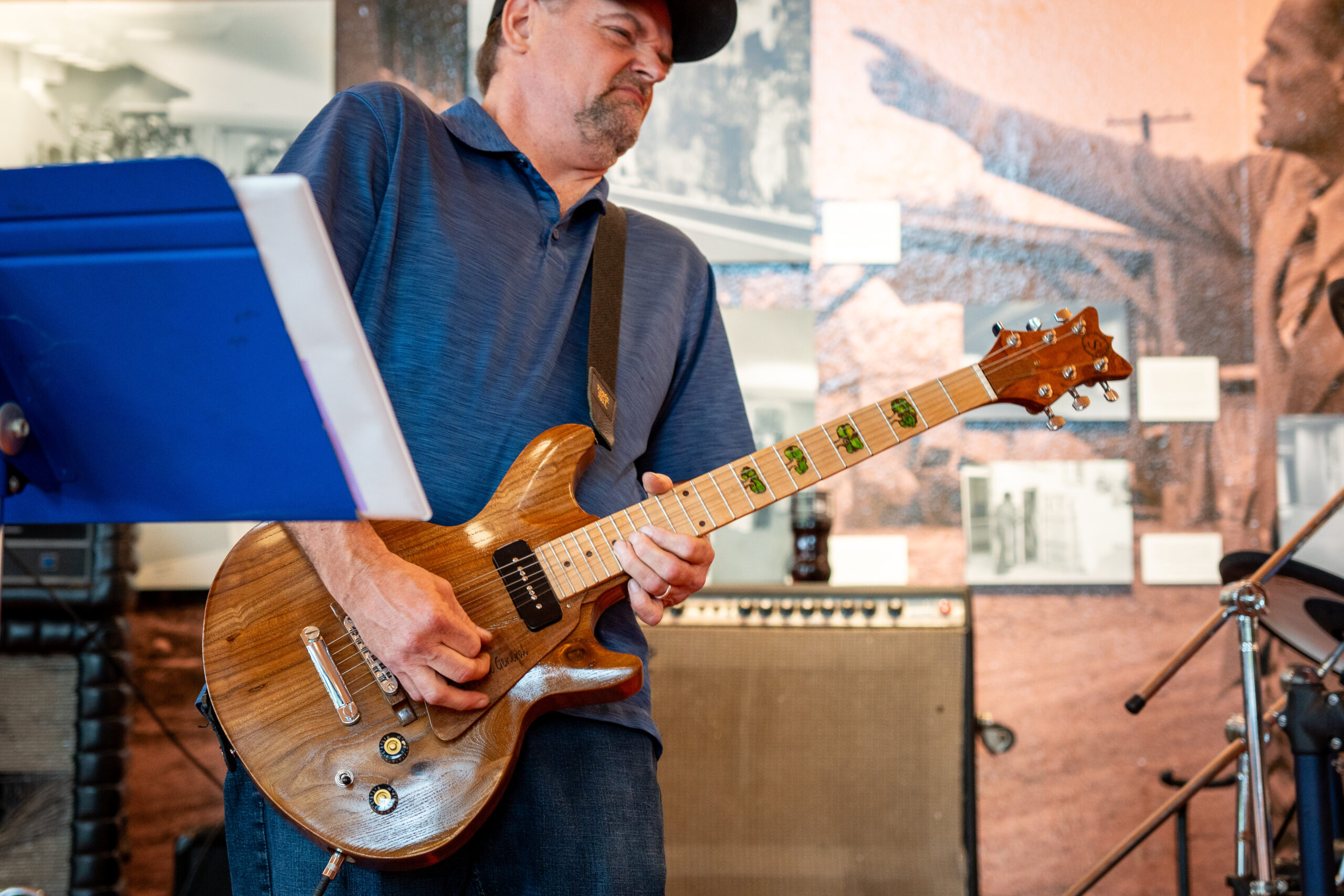 A man plays a guitar. A music stand can be seen in the foreground.
