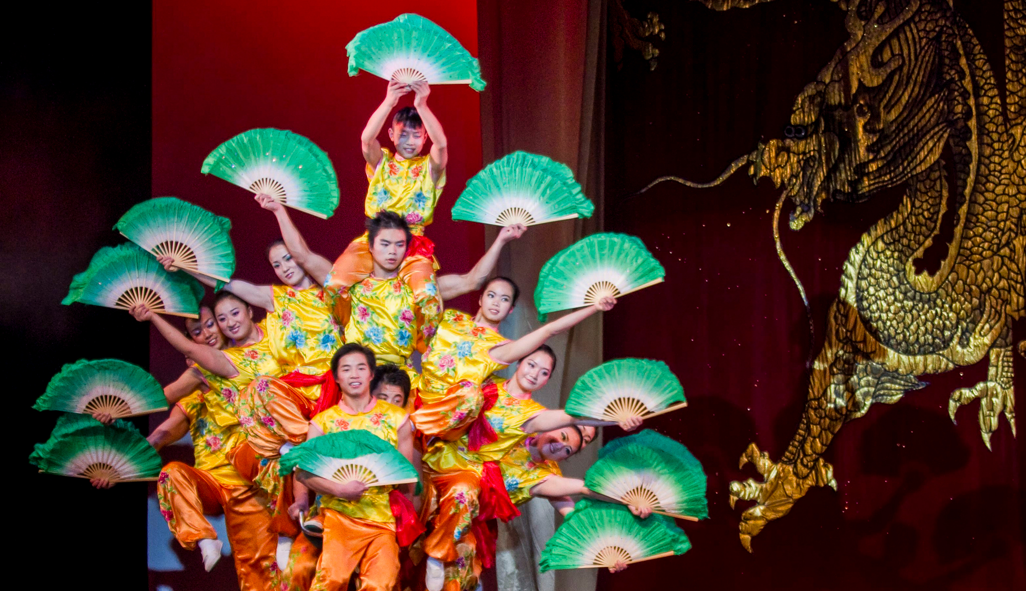 The Peking Acrobats stacked on one another's shoulders, holding colorful and fans