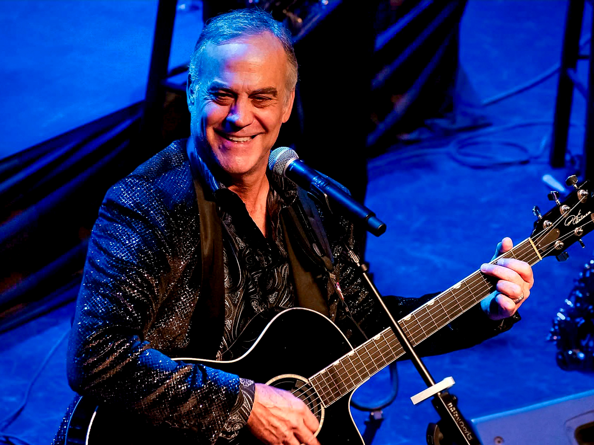 Robert Neary playing guitar and smiling in front of a microphone
