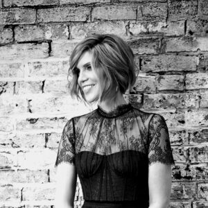 Black and white headshot of Alison Krauss standing in front of a brick wall